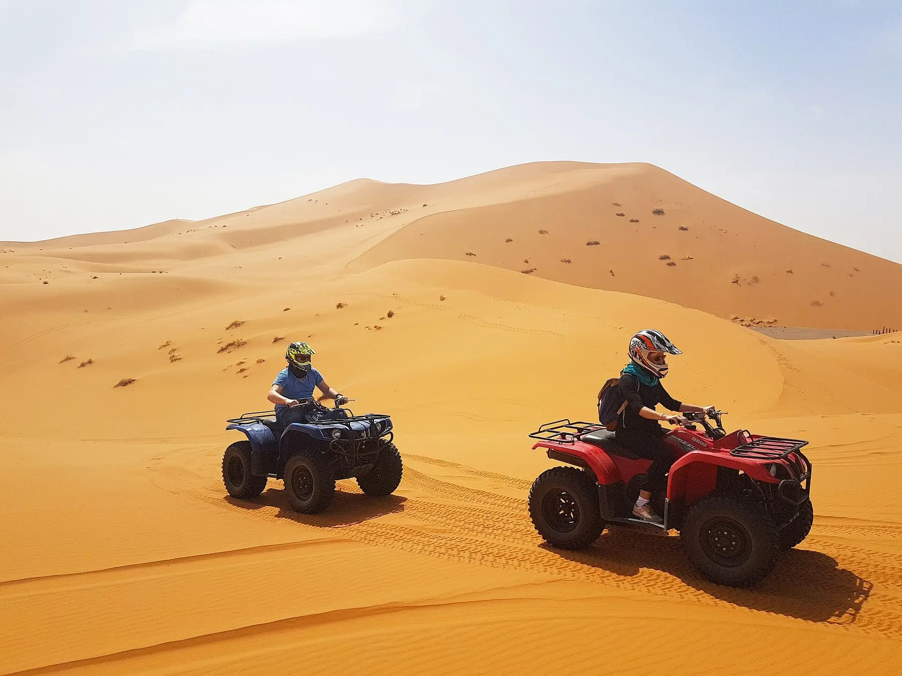 A line of quad bikes riding across sand dunes in Morocco